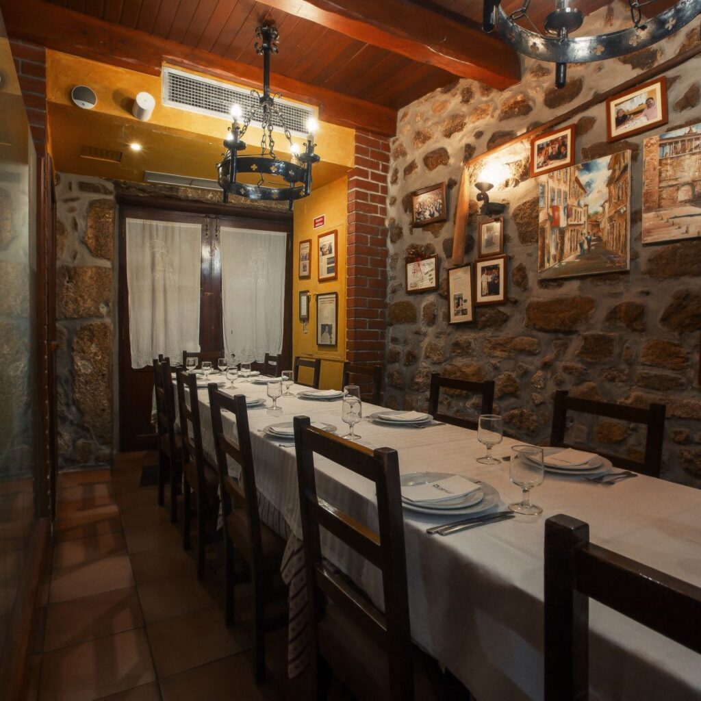 Sala do Cortiço com a mesa comprida posta, paredes de granito e candeeiro de ferro